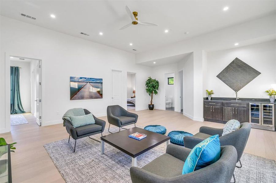 Living area with wine cooler, light wood-type flooring, a ceiling fan, recessed lighting, and bar with sink