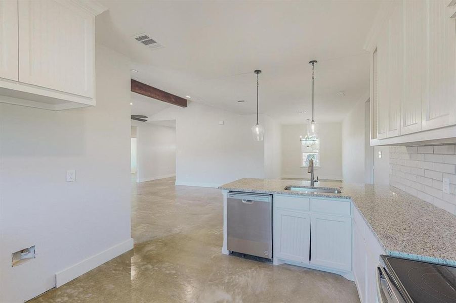 Kitchen featuring decorative backsplash, light stone counters, stainless steel appliances, sink, and white cabinets