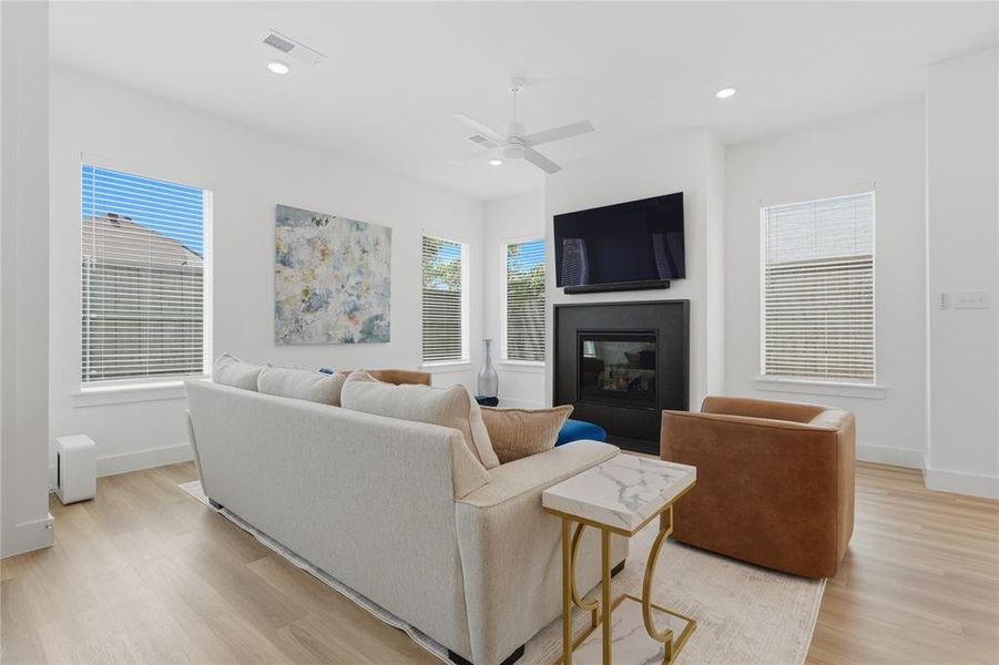 Bright living space featuring light wood-finish flooring, recessed lighting, and a ceiling fan