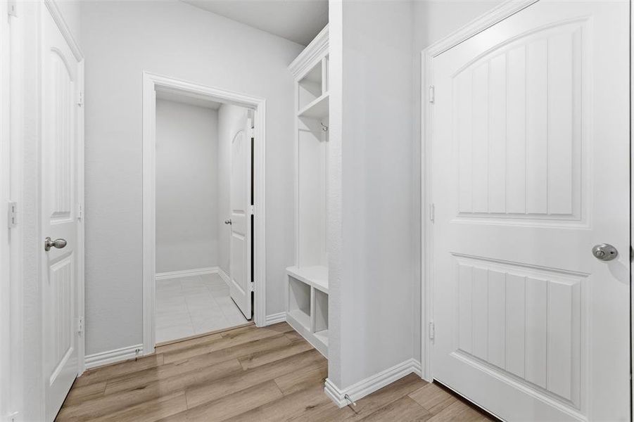 Mudroom featuring light wood-style flooring and baseboards