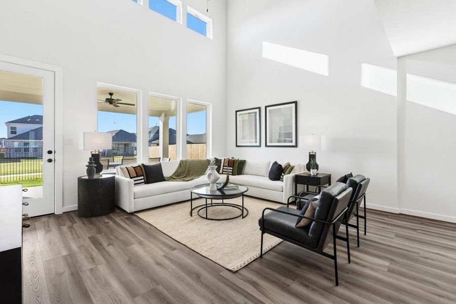 Living room with a high ceiling, light wood-style floors, and ceiling fan Living room with a high ceiling, light wood-style floors, and ceiling fan