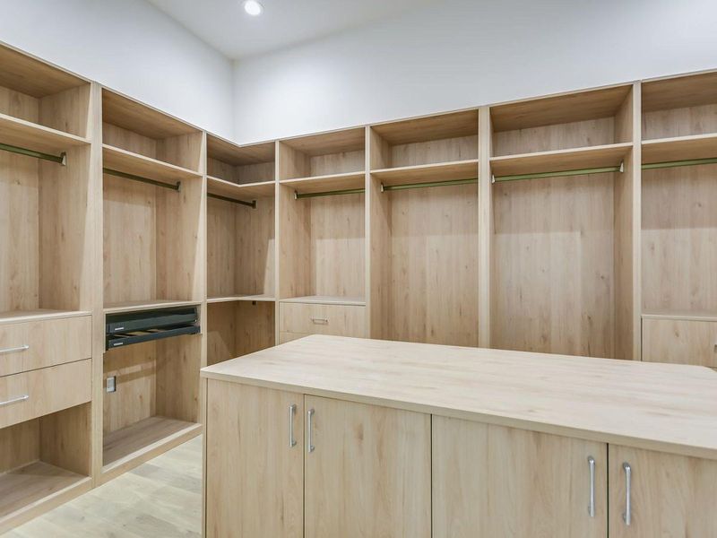 Ample storage solutions abound in this well-appointed walk-in wardrobe, featuring custom built-ins and a central island. Ample storage solutions abound in this well-appointed walk-in wardrobe, featuring custom built-ins and a central island.