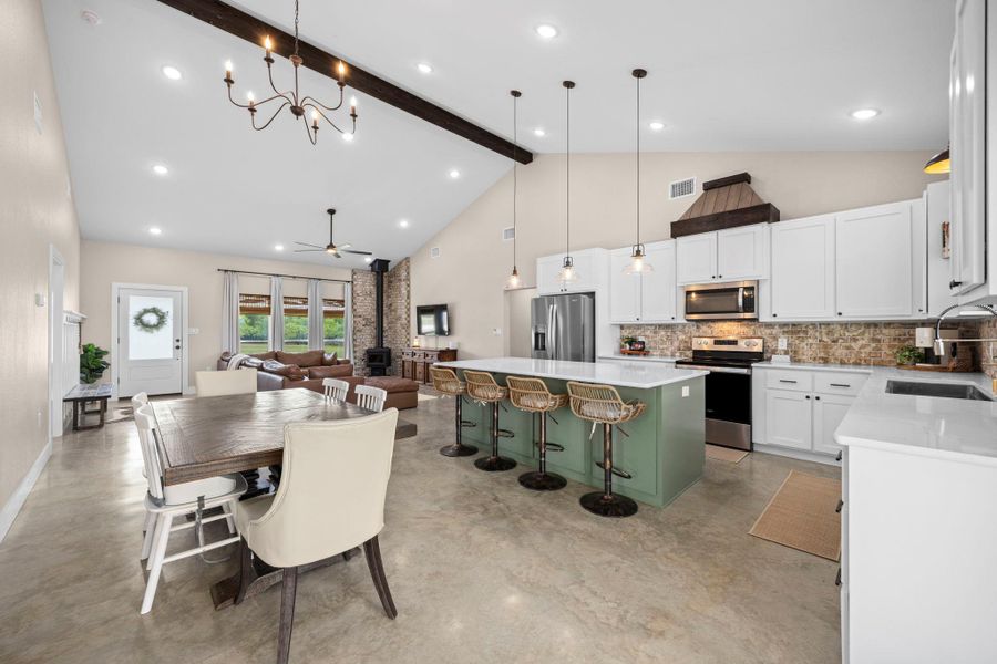 Kitchen with a wood stove, stainless steel appliances, open floor plan, a kitchen island, and concrete floors