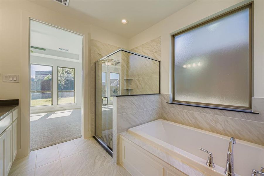 Full bathroom featuring a garden tub, light tile patterned floors, a shower stall, light colored carpet, and vanity Full bathroom featuring a garden tub, light tile patterned floors, a shower stall, light colored carpet, and vanity