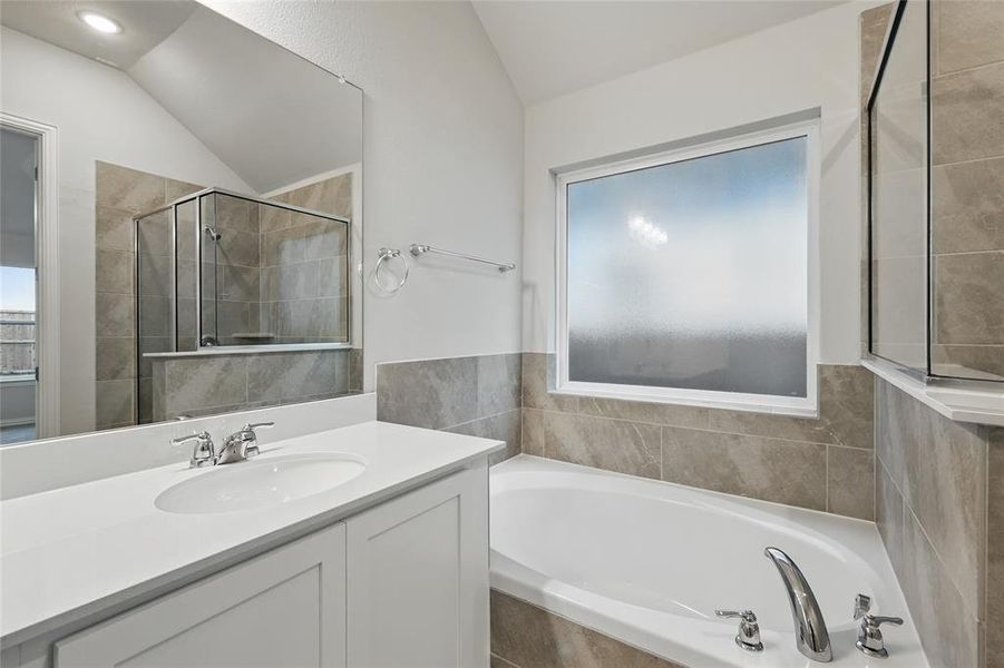 Full bath with lofted ceiling, a bath, vanity, and a stall shower Full bath with lofted ceiling, a bath, vanity, and a stall shower