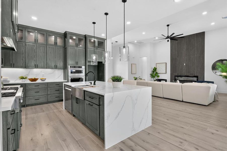 Kitchen featuring gray wood cabinetry, white stone countertops, and a waterfall island
