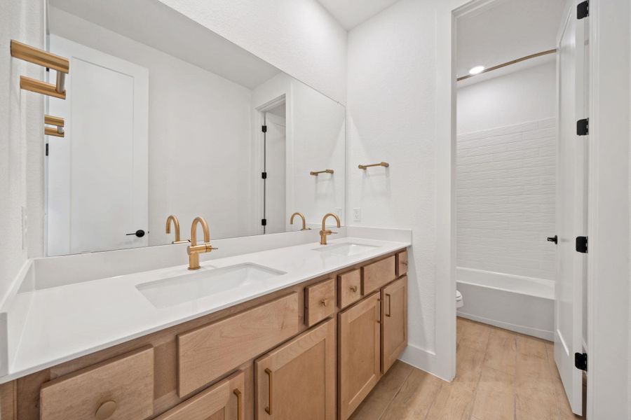Bathroom featuring double vanity, light wood-style flooring, and  shower combination