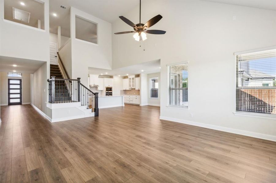 Unfurnished living room with light wood-type flooring, high vaulted ceiling, and plenty of natural light