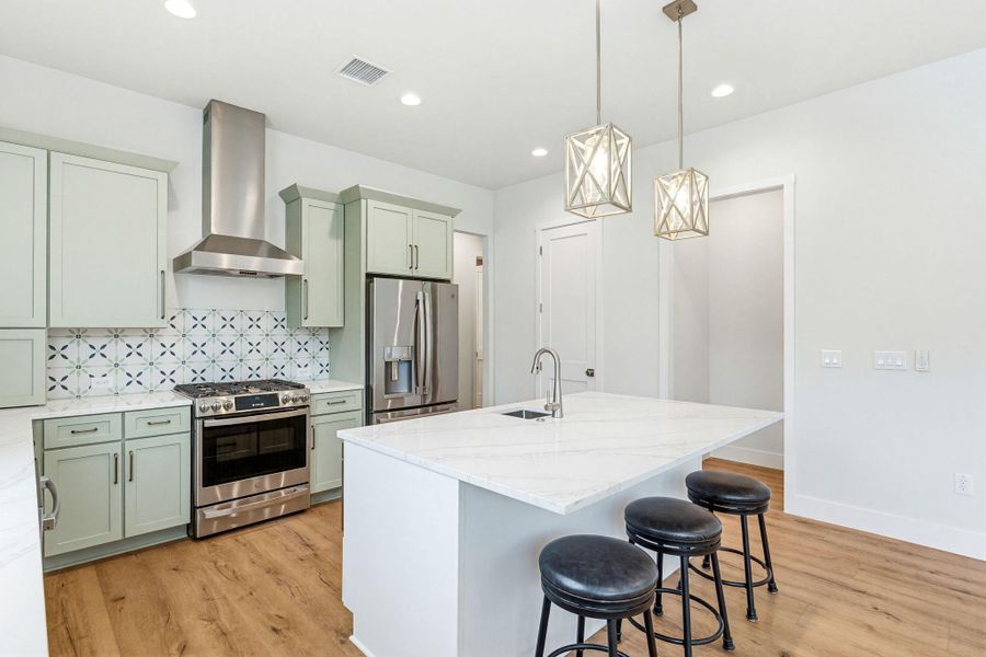 A well-appointed kitchen features stainless steel appliances, a center island with seating, and elegant pendant lighting.