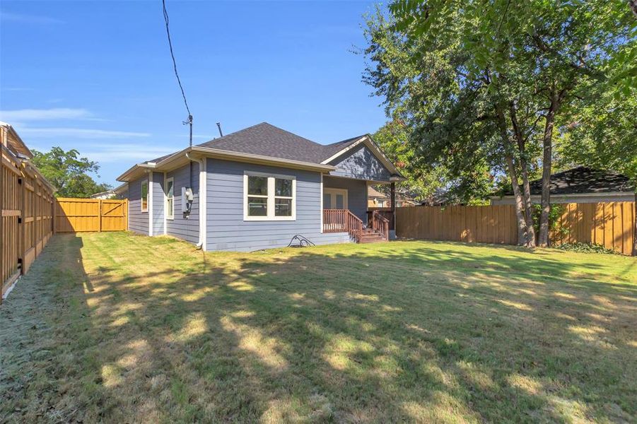 Rear view of property featuring a fenced backyard and a shingled roof