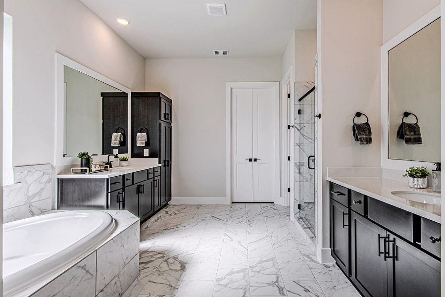 Luxurious primary bath with dual vanities, a soaking tub, and a glass-enclosed shower