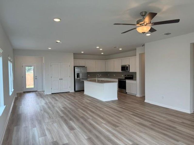 Open-concept living space featuring wood-finish flooring, recessed lighting, and a ceiling fan with light fixture