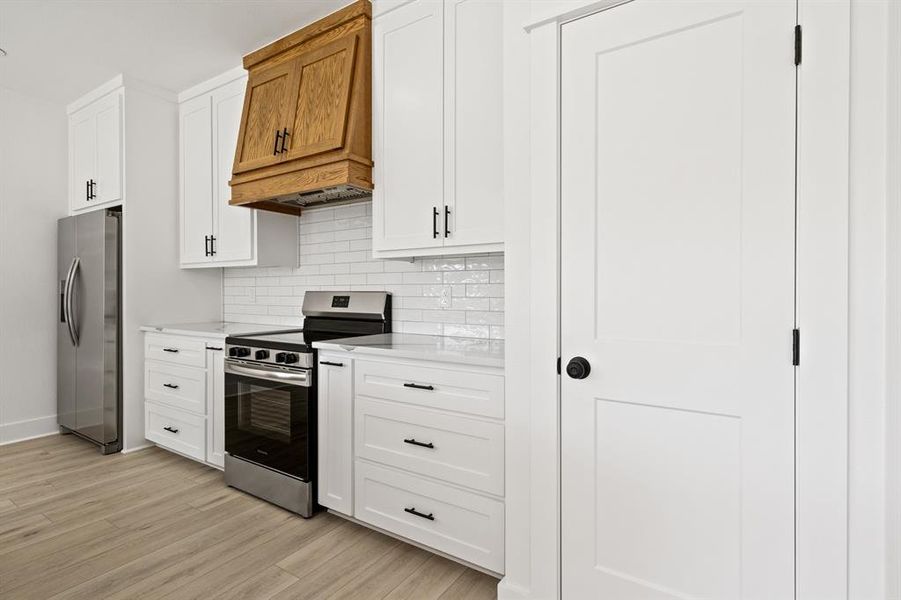 Kitchen with appliances with stainless steel finishes, white cabinetry, and tasteful backsplash