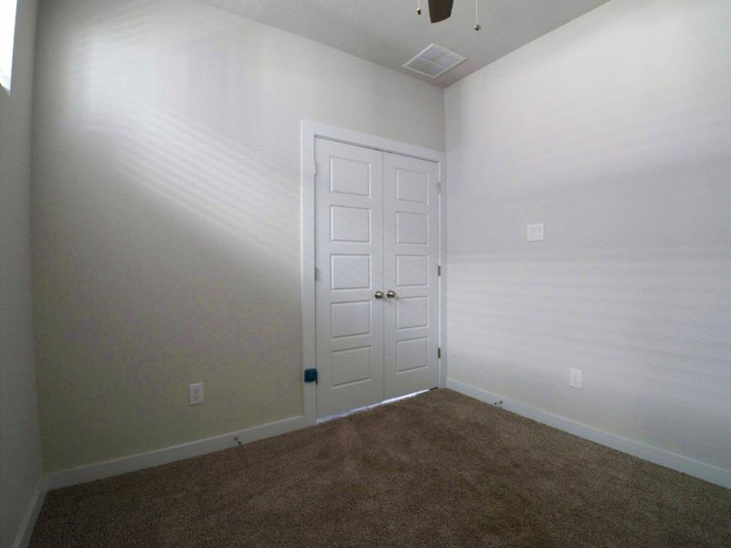 Empty room featuring carpet floors and a ceiling fan Empty room featuring carpet floors and a ceiling fan
