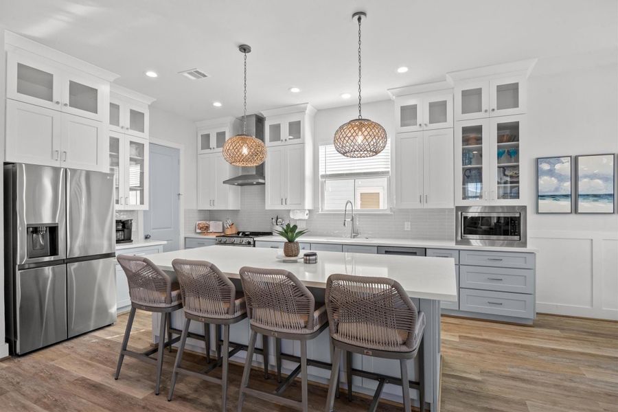 This incredible kitchen designed with two-toned cabinetry, eye-catching coastal pendant lighting, and a spacious oversized island, perfect for both cooking and entertaining.