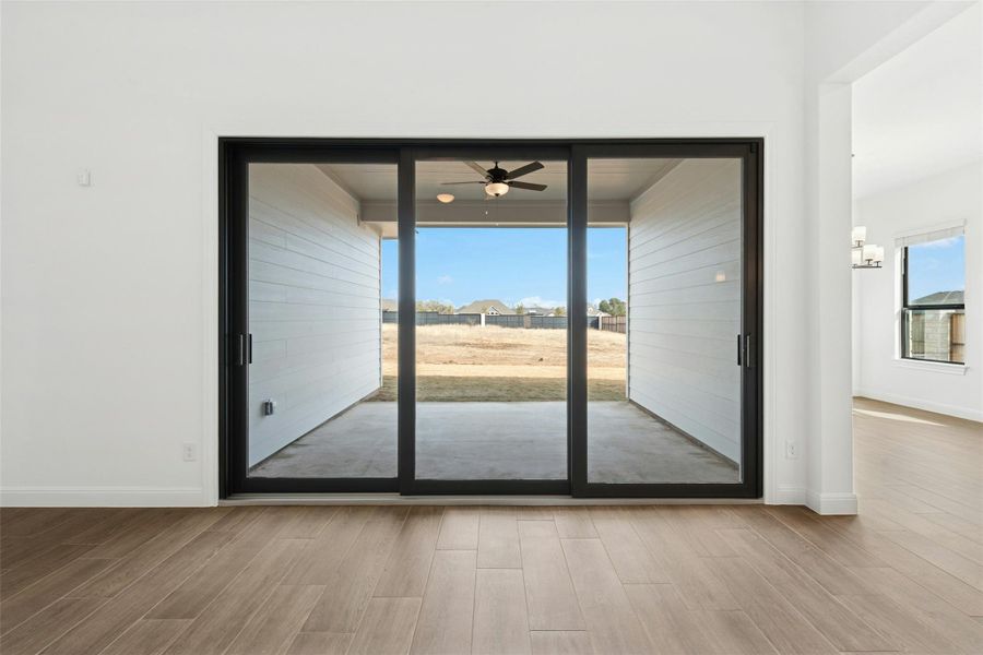 Doorway to outside featuring wood finished floors, a ceiling fan, a sunroom, and a residential view