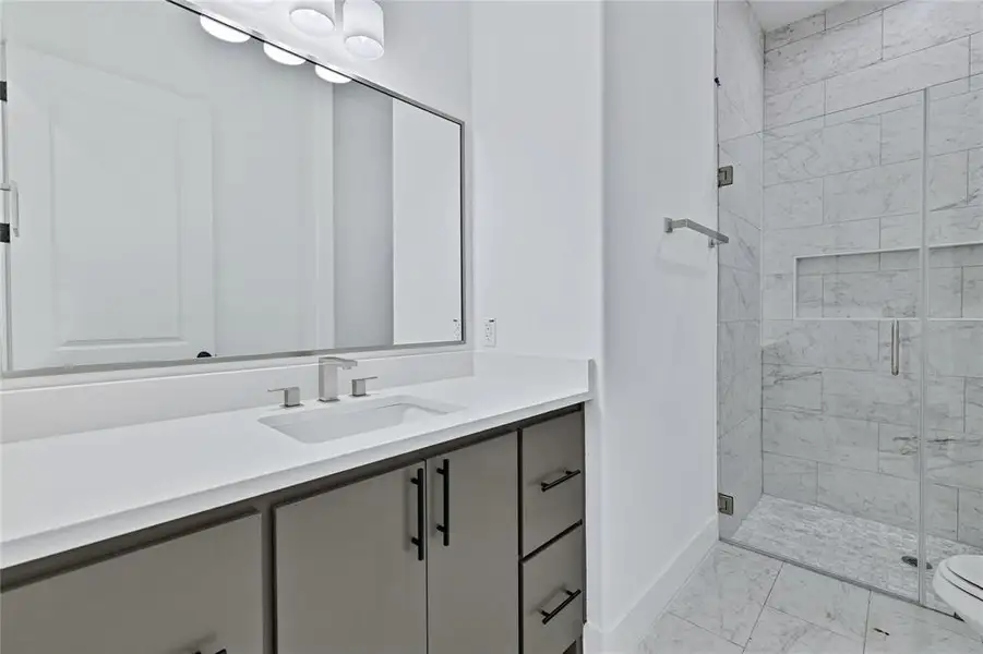 Full bath with a marble finish shower, vanity, and light marble finish flooring