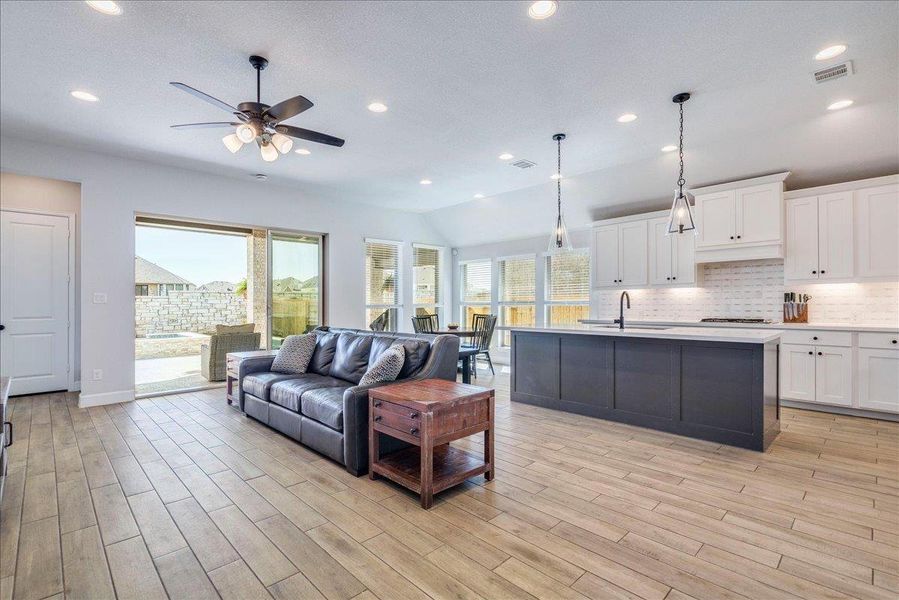 Living room featuring light wood-style floors, lofted ceiling, a ceiling fan, and recessed lighting