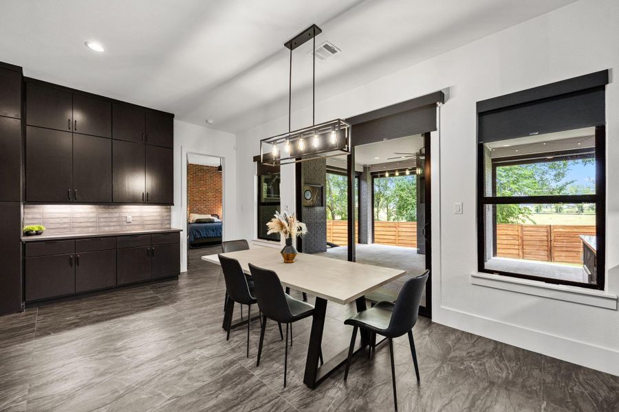 This modern dining area features sleek black cabinetry, a stylish light fixture, and large windows offering abundant natural light. The open layout seamlessly connects to an outdoor patio, creating an inviting space for entertaining. This modern dining area features sleek black cabinetry, a stylish light fixture, and large windows offering abundant natural light. The open layout seamlessly connects to an outdoor patio, creating an inviting space for entertaining.