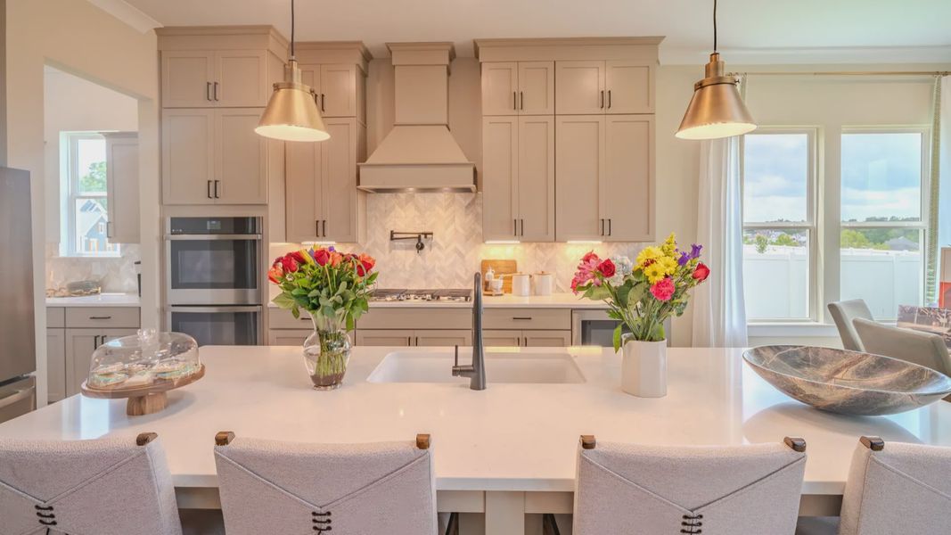Kitchen with tile backsplash, quartz countertops, and pendant lighting Kitchen with tile backsplash, quartz countertops, and pendant lighting