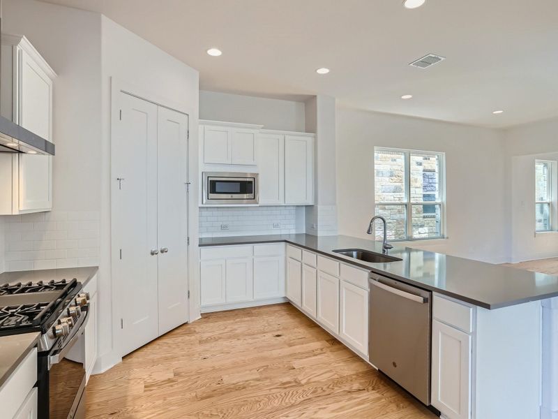 Kitchen with sink, stainless steel appliances, kitchen peninsula, and white cabinets