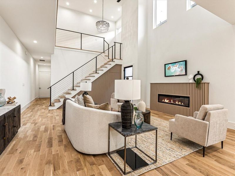 Living room with light hardwood / wood-style flooring and a high ceiling