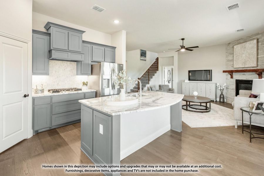 Kitchen with gray cabinets, marble island with sink, open to living room with stone fireplace and hardwood floors Kitchen with gray cabinets, marble island with sink, open to living room with stone fireplace and hardwood floors