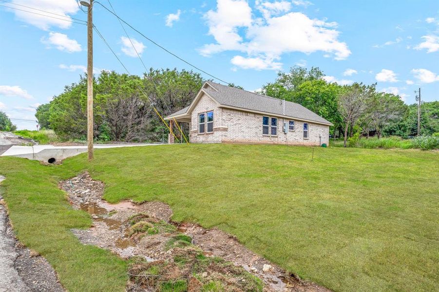 View of home's exterior featuring brick siding and a yard View of home's exterior featuring brick siding and a yard