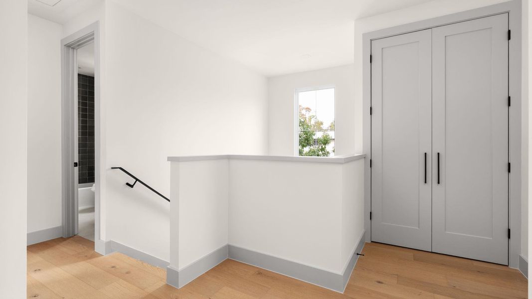 Hallway with an upstairs landing and light wood finished floors