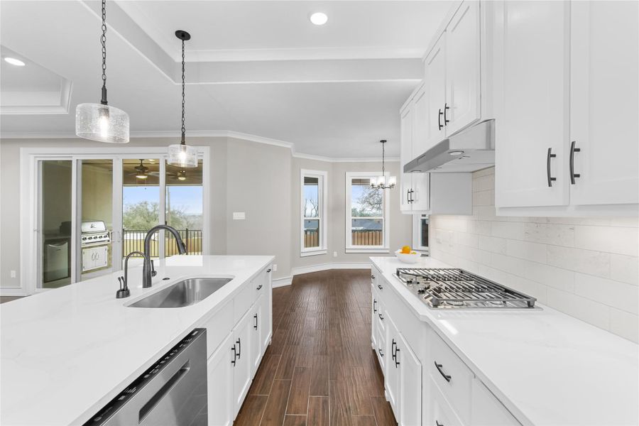Kitchen featuring a sink, under cabinet range hood, appliances with stainless steel finishes, baseboards, and healthy amount of natural light Kitchen featuring a sink, under cabinet range hood, appliances with stainless steel finishes, baseboards, and healthy amount of natural light