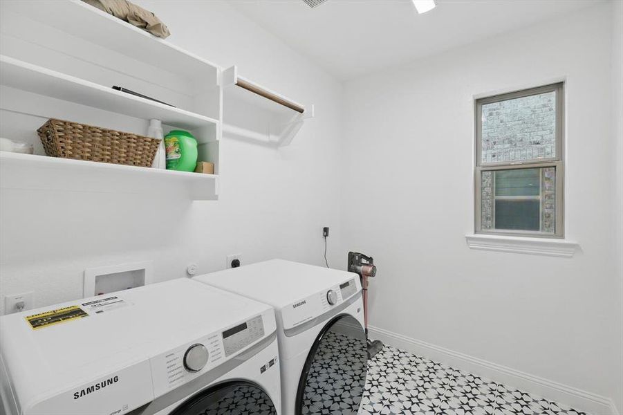 laundry area, washing machine and dryer, room for the freezer, and tile patterned floors