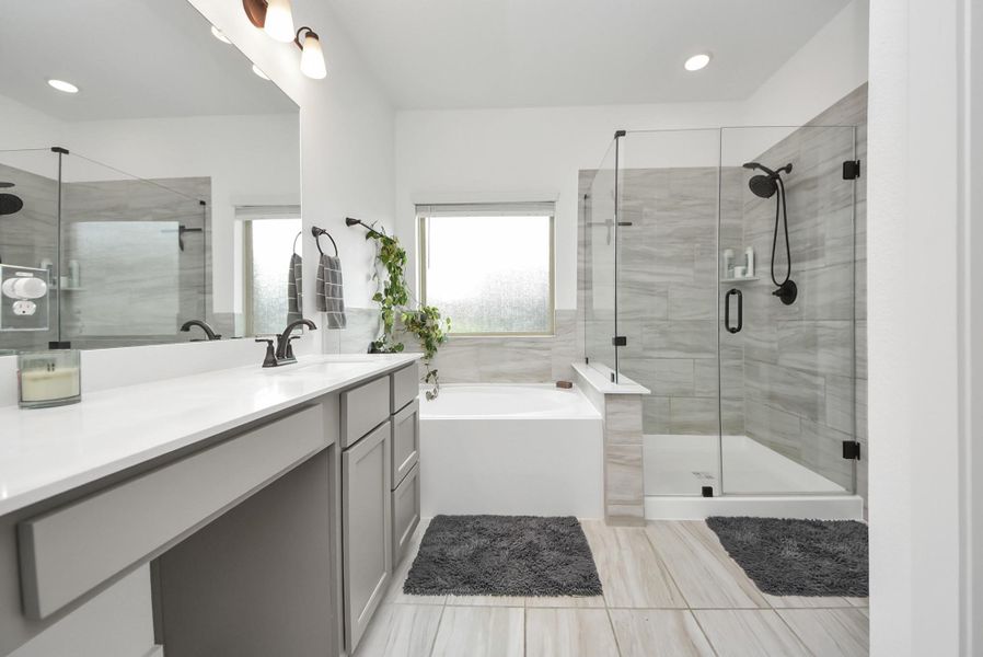Spacious primary bathroom, featuring the garden tub, showing, and double sinks.