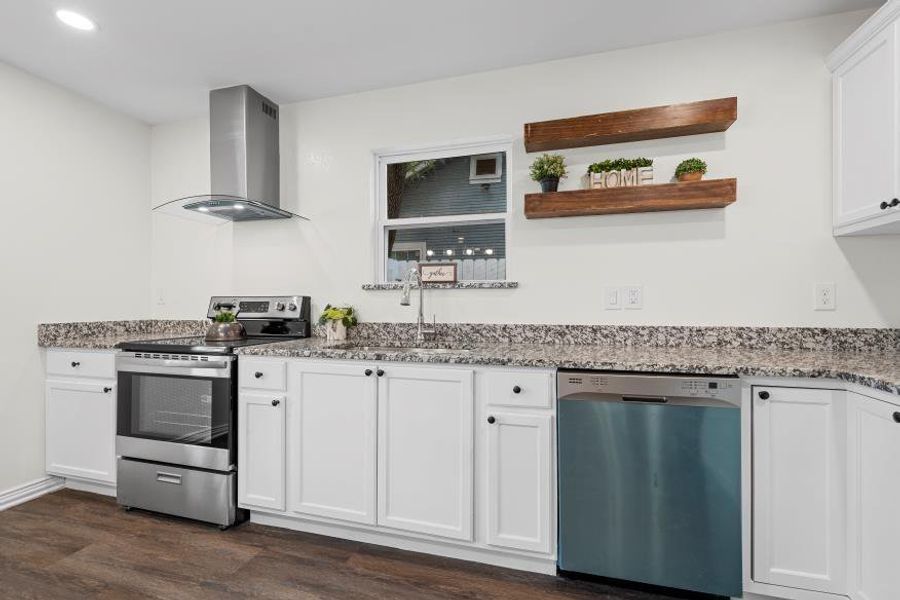 Kitchen featuring stainless steel appliances, extractor fan, stone countertops, and white cabinets Kitchen featuring stainless steel appliances, extractor fan, stone countertops, and white cabinets