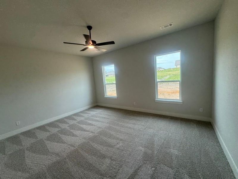 Spacious room featuring vaulted ceilings, patterned carpeting, and two large windows Spacious room featuring vaulted ceilings, patterned carpeting, and two large windows