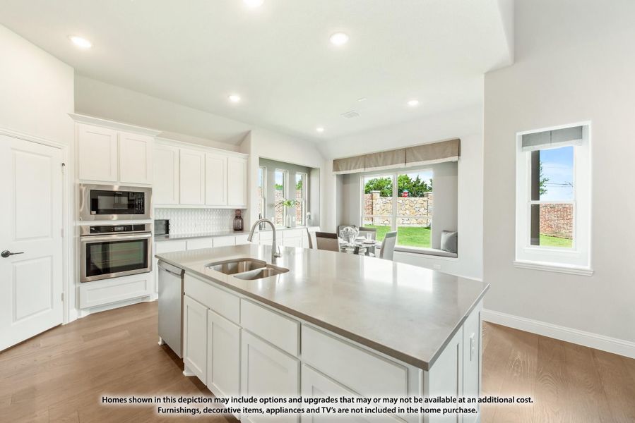 Kitchen with white cabinets, center island with sink, stainless steel appliances, and hardwood floors open to dining area.