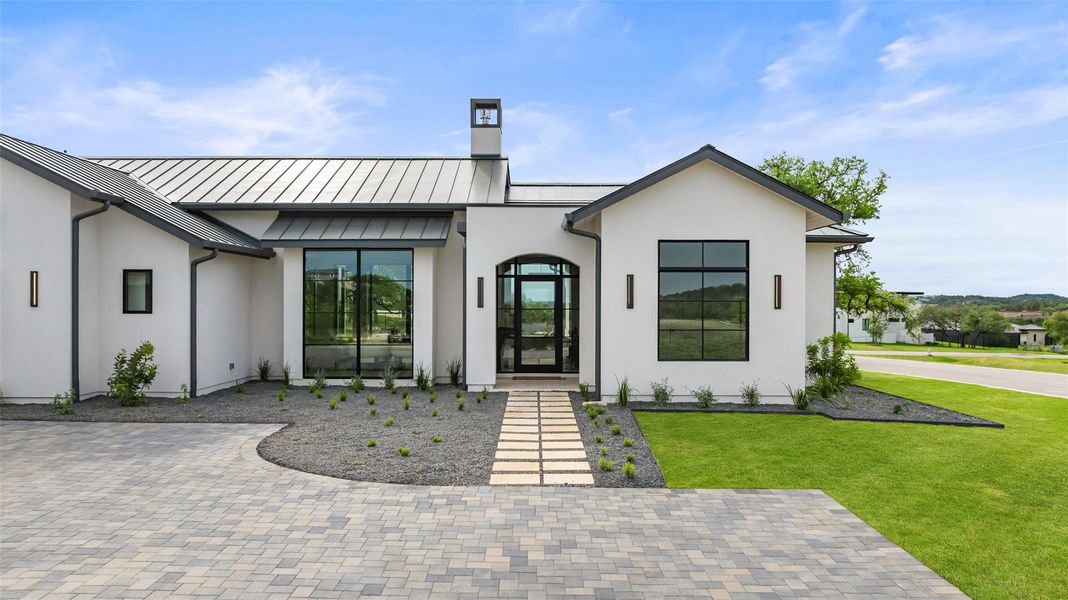 Rear view of house with a chimney, a standing seam roof, a lawn, and stucco siding Rear view of house with a chimney, a standing seam roof, a lawn, and stucco siding