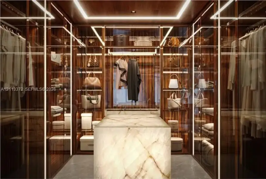 Custom walk-in closet featuring floor-to-ceiling wood cabinetry, integrated linear LED lighting, glass-fronted storage displays, and a central stone island with a polished finish
