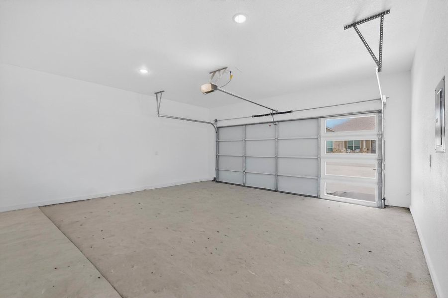 Garage featuring electric panel and baseboards