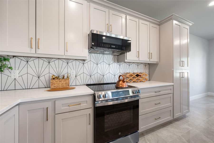 Kitchen with stainless steel appliances, backsplash, light marble finish flooring, and light stone countertops