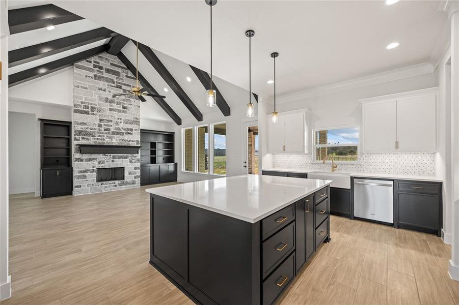 Dual tone kitchen featuring dual tone cabinetry, a kitchen island, hanging light fixtures, a fireplace, and stainless steel dishwasher