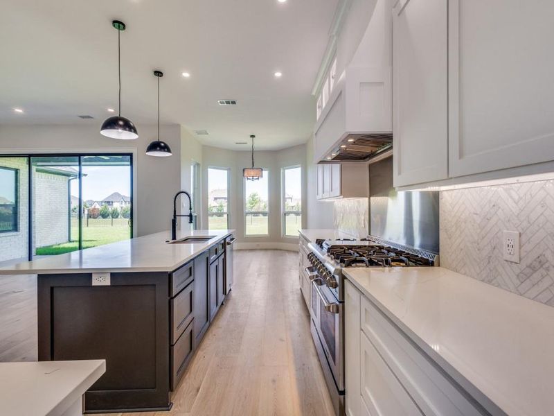 Kitchen featuring stainless steel appliances, a sink, light wood-style floors, decorative backsplash, and recessed lighting