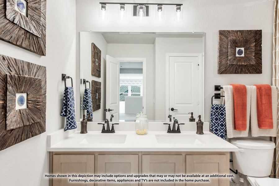 Bathroom with double sink vanity, white countertop, large mirror, and overhead light bar above tan cabinets