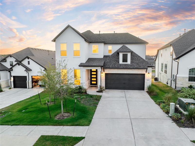 View of front of home with a shingled roof, a garage, stone siding, concrete driveway, and a front yard