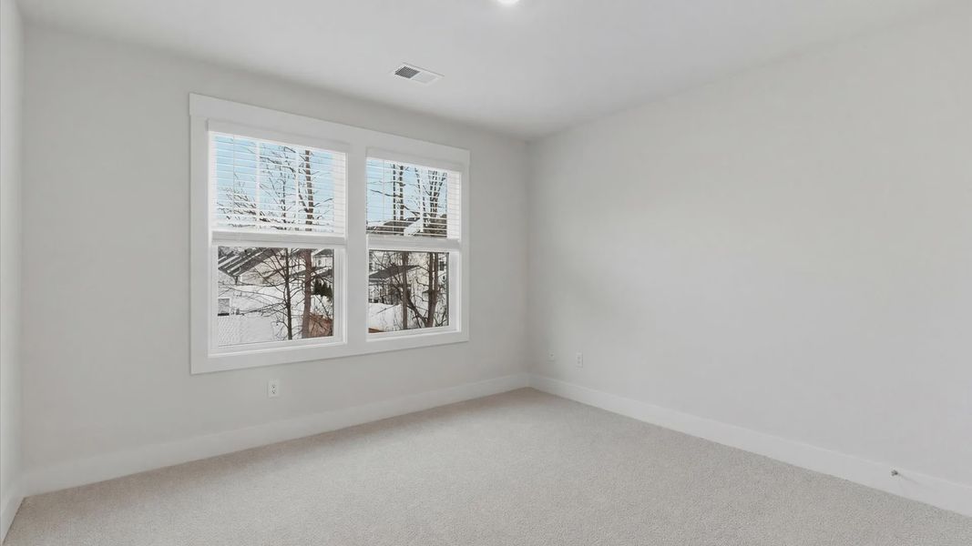 Accomplished design in this restful bedroom featuring plush carpet and oversized window views at Pelham Crossing