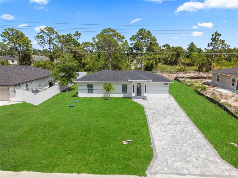 Contemporary single-story exterior with white siding, dark shingle roof, and paver driveway Contemporary single-story exterior with white siding, dark shingle roof, and paver driveway