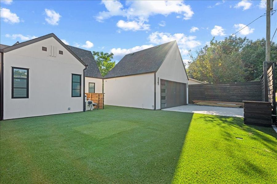 View of side of property with an outbuilding, a fenced backyard, a garage, a shingled roof, and stucco siding