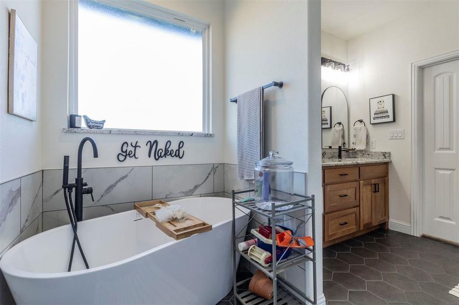 Bathroom featuring vanity, a tub, a healthy amount of sunlight, and tile patterned floors