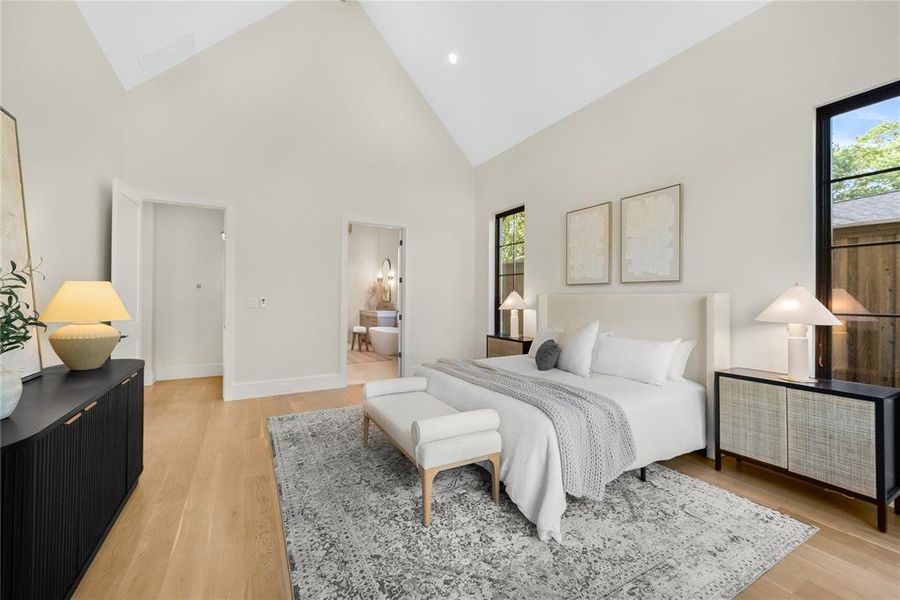 Vaulted ceiling bedroom featuring wood-finish flooring and black-framed windows