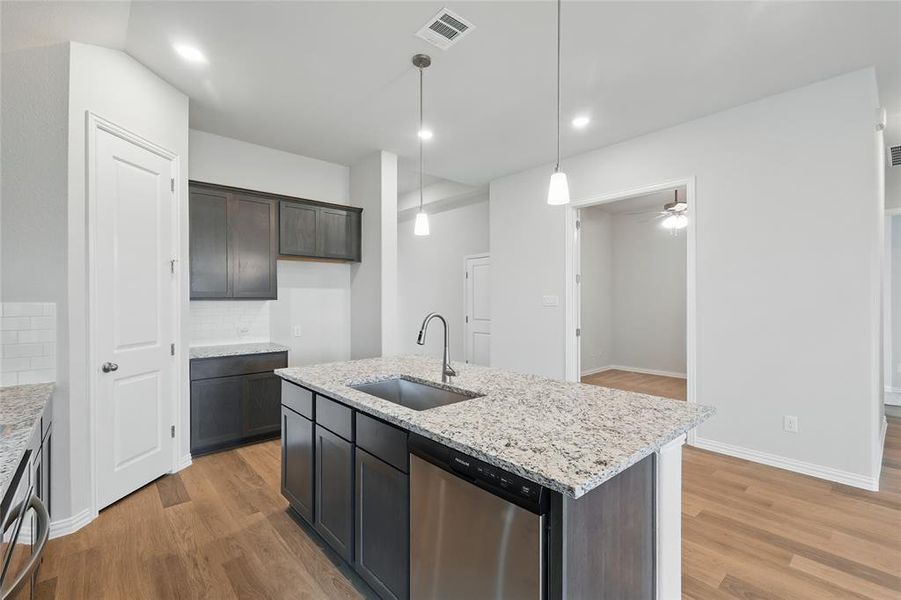 Kitchen featuring a sink, stainless steel dishwasher, light wood-style floors, tasteful backsplash, and recessed lighting Kitchen featuring a sink, stainless steel dishwasher, light wood-style floors, tasteful backsplash, and recessed lighting