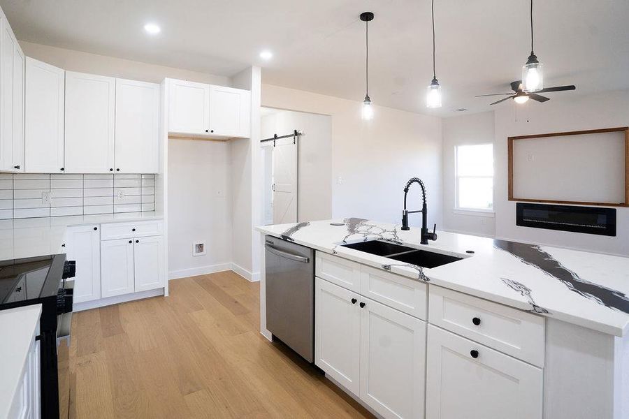 Kitchen featuring a barn door, stainless steel appliances, white cabinets, and recessed lighting